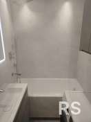 Материалы: Керамическая плитка светлых тонов, акриловая ванна, смесители, душевая система, умывальник с тумбой.
Процесс: Укладка плитки на стены, монтаж сантехники, установка душевой системы и подключение коммуникаций.